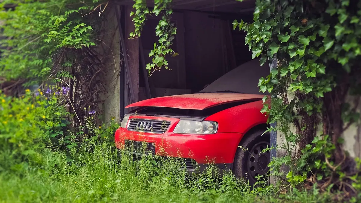 Épave de voiture abandonnée dans un garage désaffecté